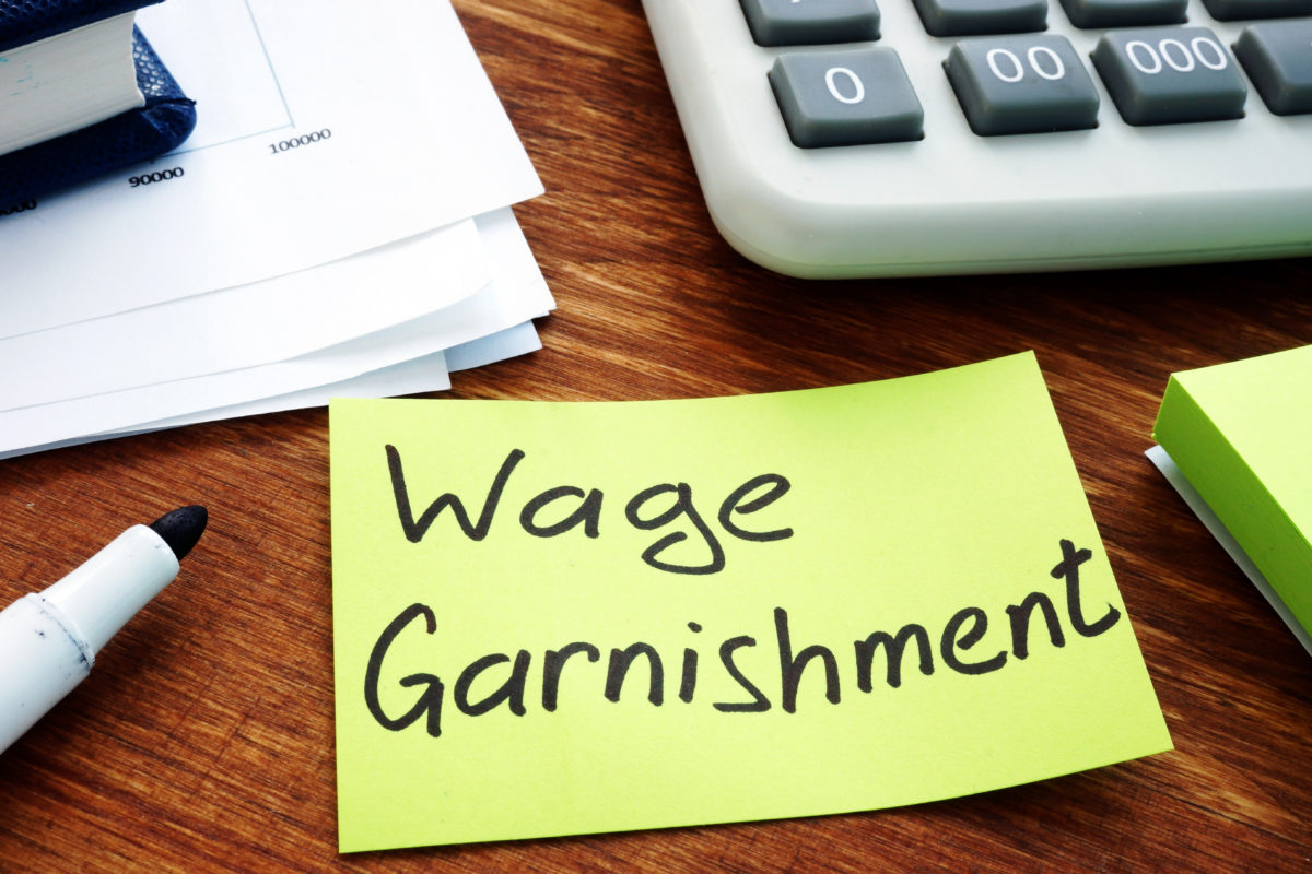 "wage garnishment" written on a sticky note near credit card bills