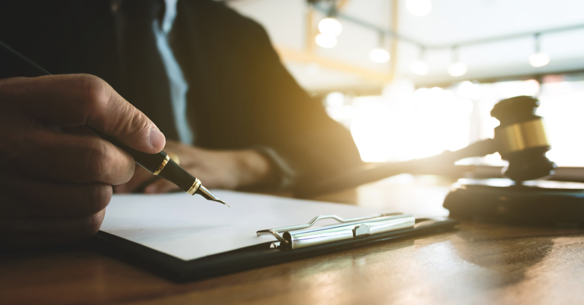 A lawyer writing with a pencil and with a gavel on his side