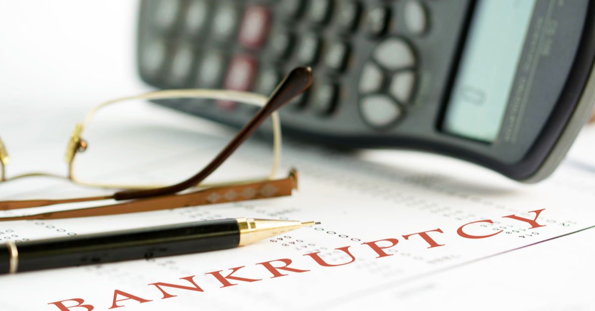 a pen, calculator and reading glasses on bankruptcy documents.