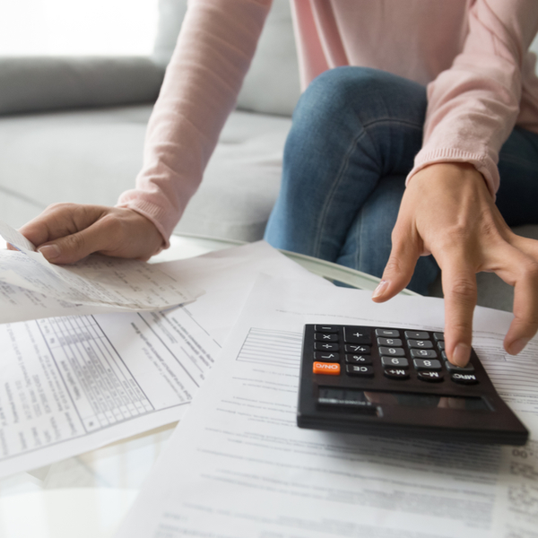 Woman holding paper bills using calculator