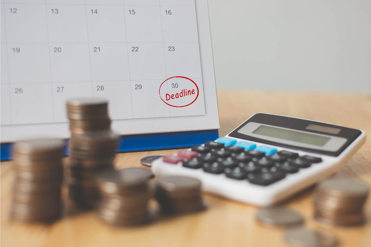 Stacked coins, calendar with marked deadline and calculator