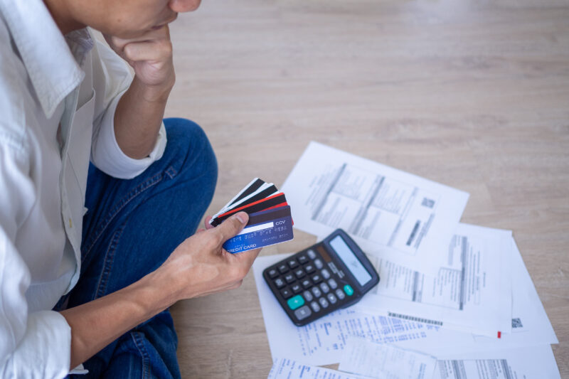 man sitting on the floor, reviewing credit card bills and debt collection papers from Hayt, Hayt & Landau