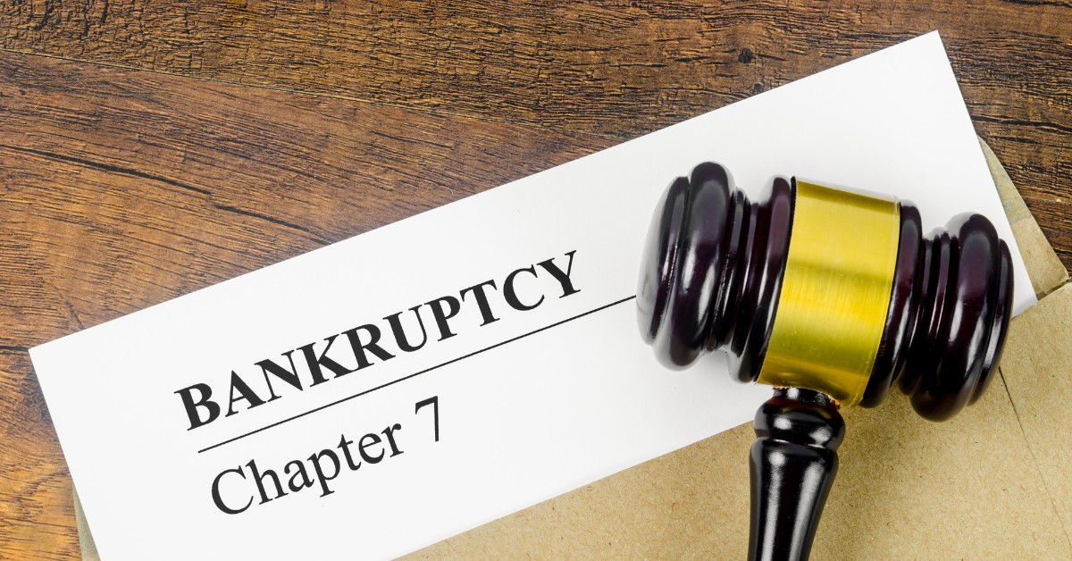A brown wooden gavel rests on a white sheet of paper with the words "BANKRUPTCY Chapter 7" printed in black.